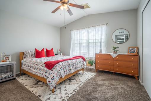 A bedroom with a bed, dresser, and ceiling fan.