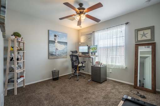 A room with a ceiling fan and a painting of a woman on the wall.