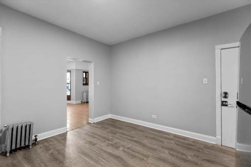 A room with a grey wall and a wooden floor.