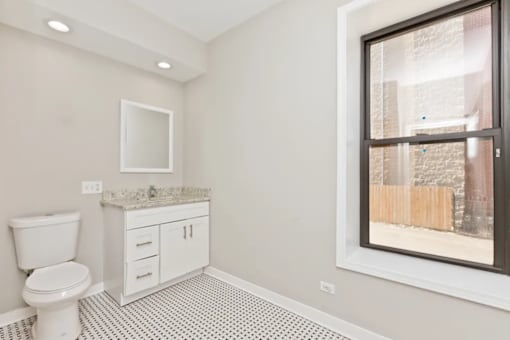 A bathroom with a toilet, sink, and a window.