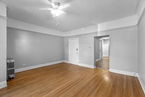 A room with a ceiling fan and wooden flooring.