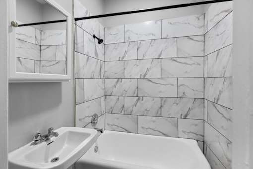 A white sink and tub in a marble tiled bathroom.