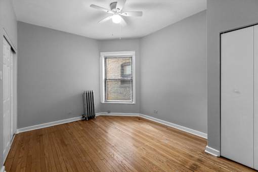 A room with a ceiling fan and a window with a radiator beneath it.