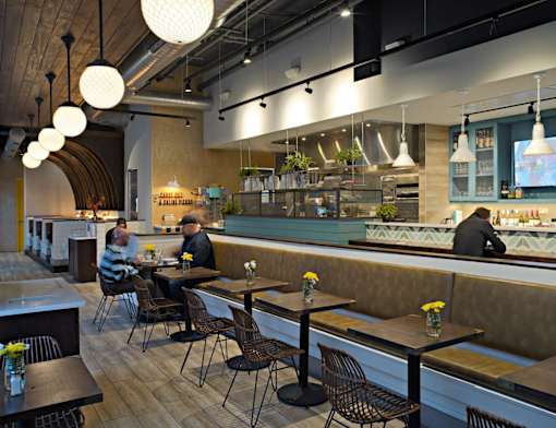 A restaurant with people sitting at tables and a counter in the background.