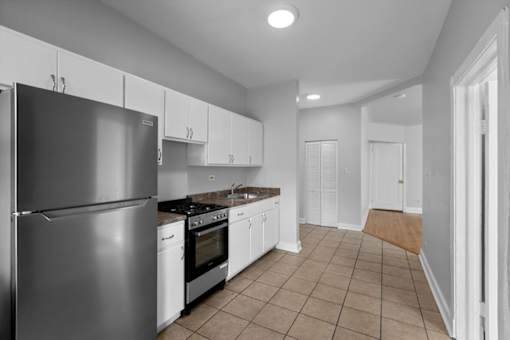 A kitchen with a refrigerator, oven, and cabinets.