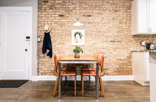A dining room with a brick wall and a table with chairs.