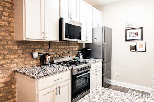 A kitchen with a brick wall and a granite countertop.