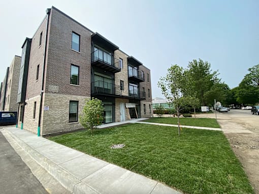 A modern brick apartment building with a green lawn in front.