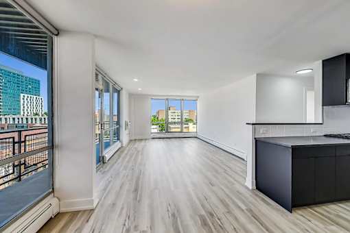 A spacious room with wooden flooring and a large window overlooking a cityscape.