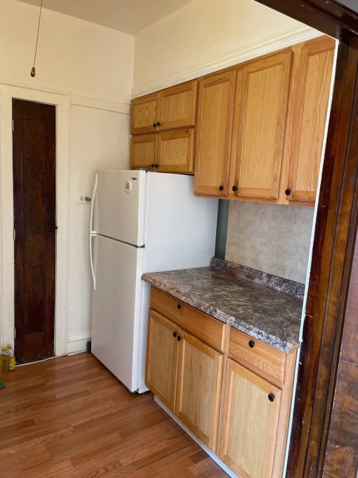 a kitchen with a refrigerator and wooden cabinets