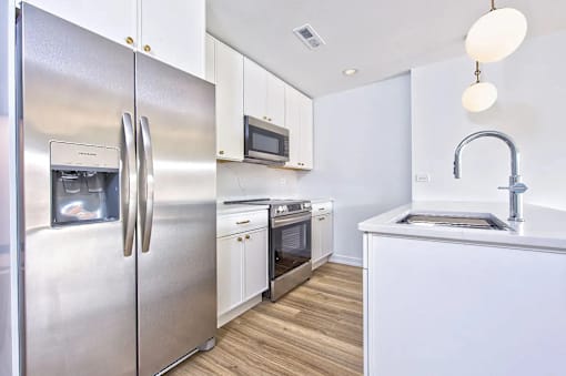 A modern kitchen with a stainless steel refrigerator and white cabinets.