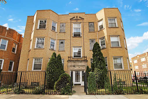 A large brick building with a black iron fence in front.