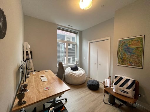 A room with a wooden table, a bean bag chair, and a painting on the wall.