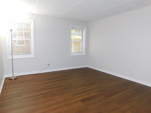 A room with wooden flooring and a window with blinds.