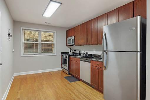 A kitchen with wooden cabinets and a stainless steel refrigerator.
