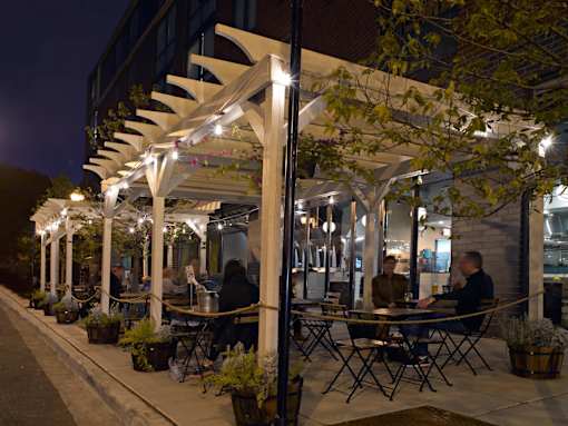 A restaurant with tables and chairs under a canopy with lights.