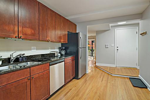 A kitchen with wooden cabinets and a black fridge.