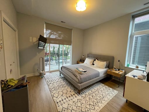 A bedroom with a bed, nightstand, and window with blinds.