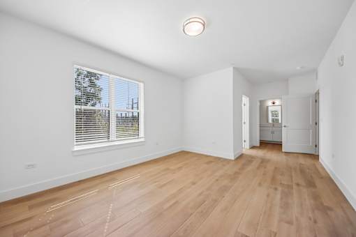 A room with wooden floors and a window with blinds.
