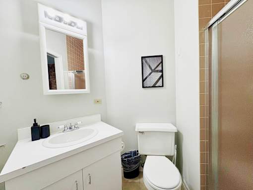 A white bathroom with a toilet, sink, and mirror.