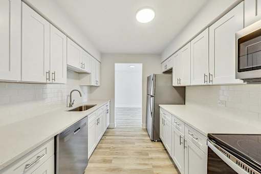 A kitchen with white cabinets and a stainless steel refrigerator.