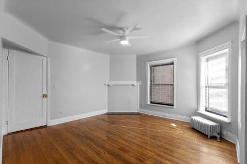 A room with a ceiling fan and a window with blinds.