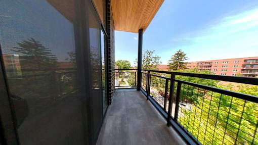 A balcony with a black railing and a view of a building across the way.