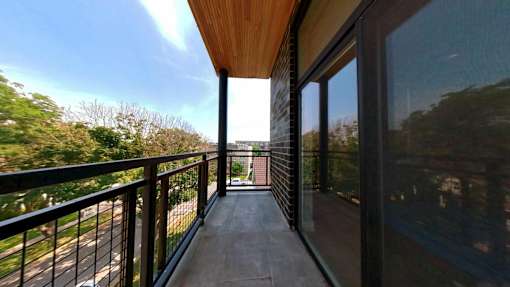 A balcony with a black railing and a wooden floor.