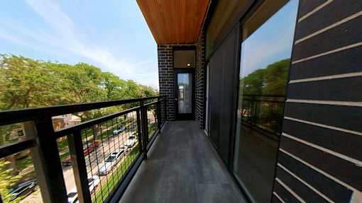 A balcony with a view of a parking lot and trees.