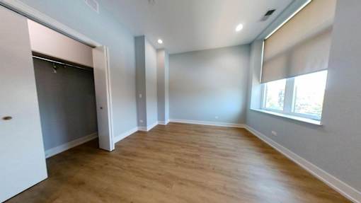 A room with wooden flooring and a window with blinds.