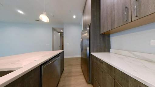A kitchen with dark wood cabinets and a marble countertop.