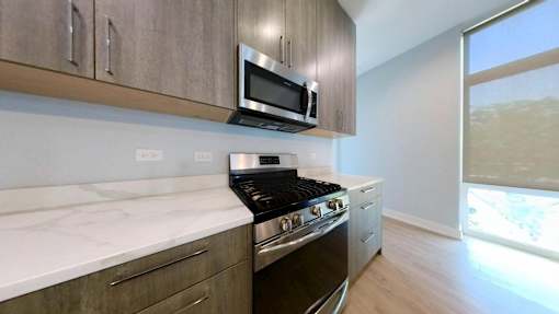 A modern kitchen with a stove, microwave, and oak cabinets.