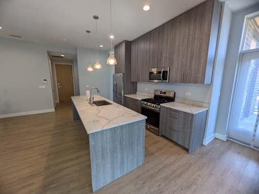 A modern kitchen with a marble island and wooden cabinets.