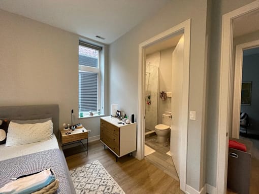 A bedroom with a bed, nightstand, and a window.
