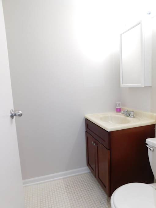 A white sink with a brown cabinet and a white toilet in a bathroom.