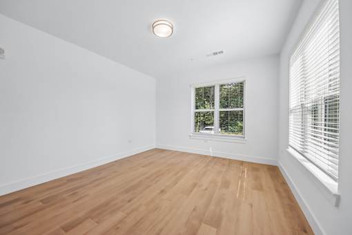 A room with wooden flooring and a window with blinds.