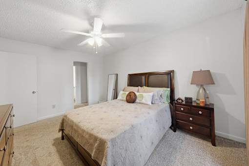A bedroom with a bed, dresser, and ceiling fan.