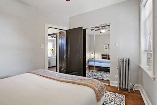 A bedroom with a bed, a mirror, and a window.