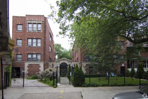 the front of a red brick building with a black fence and a gate