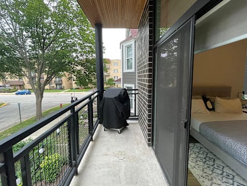 A balcony with a black railing and a mattress on a bed frame.