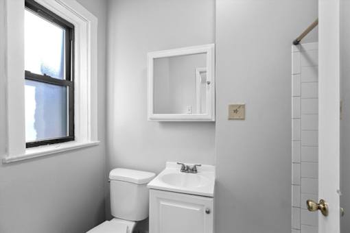 A white bathroom with a toilet, sink, and mirror.