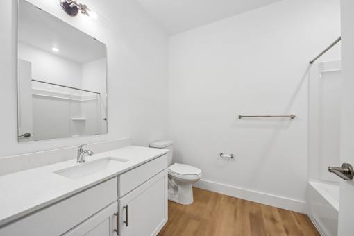 A white bathroom with a toilet, sink, and mirror.