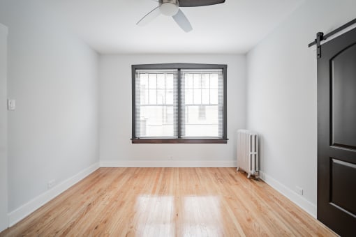 an empty room with a window and wood floors