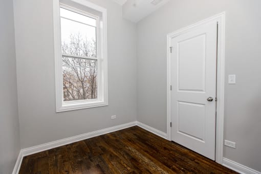 a bedroom with wood floors and a window