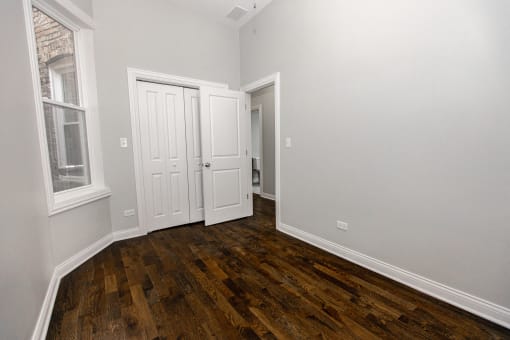 an empty bedroom with wood floors and white walls
