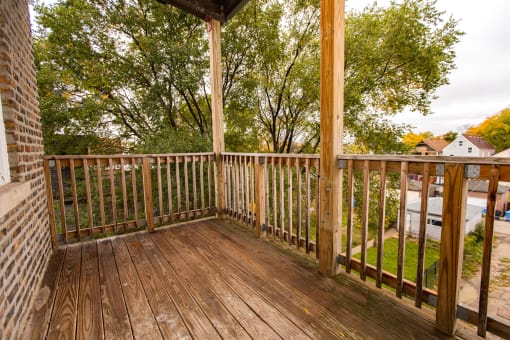 the deck of a home with wooden railing and trees
