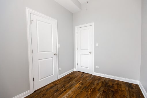 an empty room with two doors and wood floors