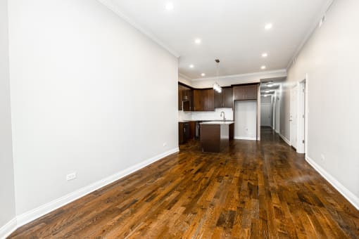 a living room and kitchen with wood floors and white walls