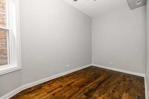 an empty room with wooden floors and a window