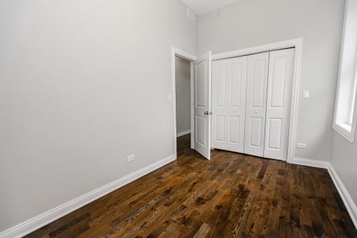 a bedroom with wood flooring and white walls and doors